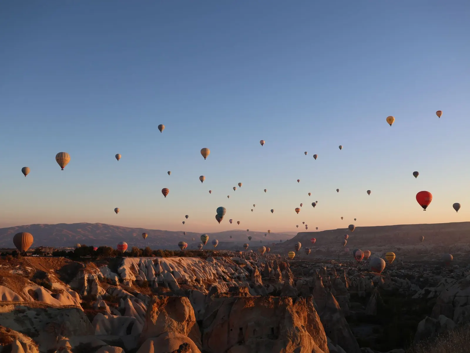 Hot air balloons rising over Cappadocia at sunrise